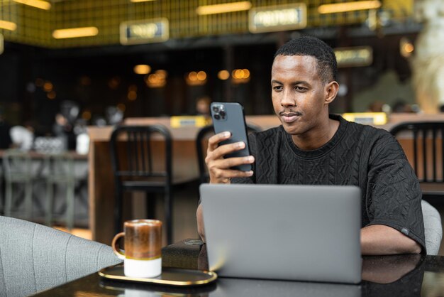 Portrait of handsome young African man using laptop computer in coffee shop