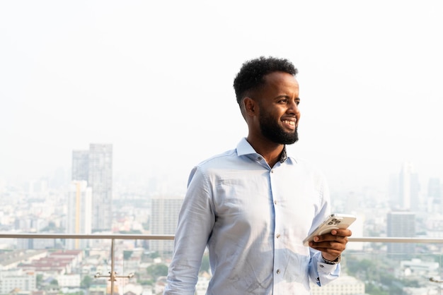 Portrait of handsome young African man using mobile phone