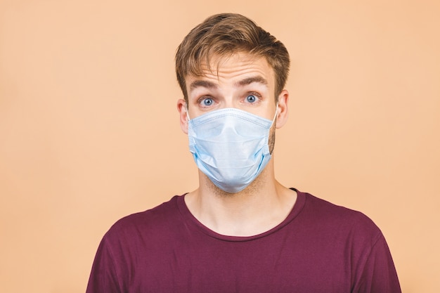 Portrait of handsome young amazed man with surgical medical mask