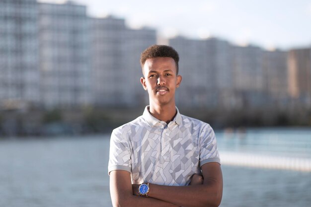 Portrait of handsome young black man among high aparments with copy space