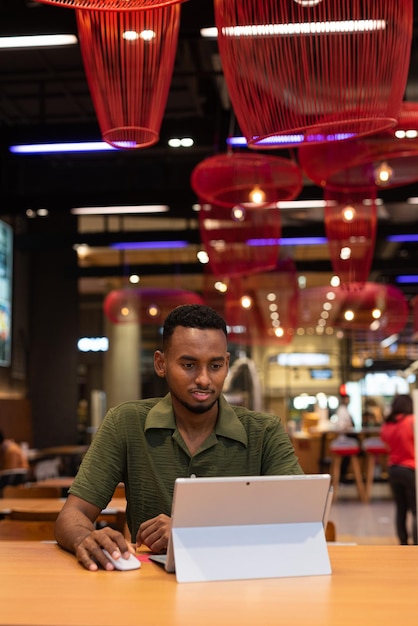 Portrait of handsome young black man using laptop computer in coffee shop