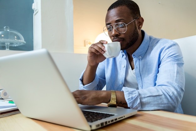 Portrait of handsome young black man working with laptop at home.