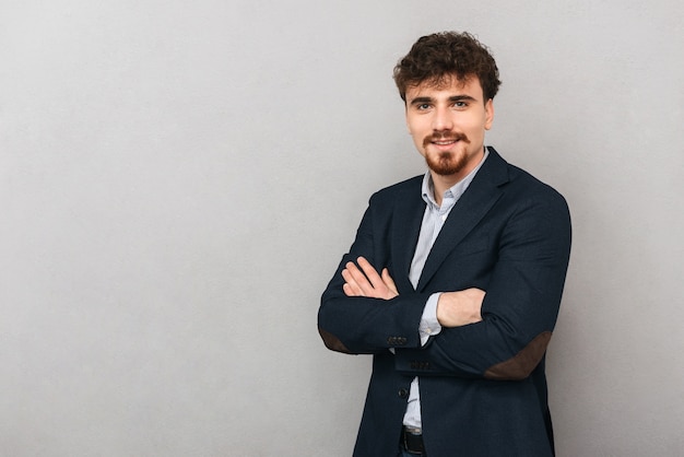 portrait of a handsome young business man isolated over grey wall.