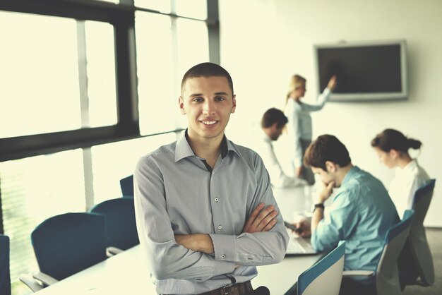 Portrait of a handsome young  business man  on a meeting in offce with colleagues in background