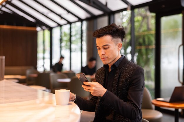 Portrait of handsome young businessman using phone in coffee shop