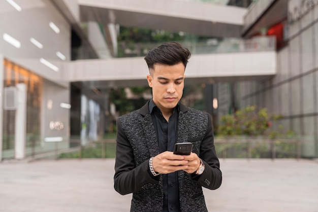 Portrait of handsome young businessman using phone