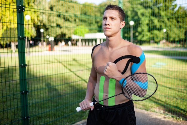 Portrait of handsome young caucasian professional tennis player with elastic tapes on body