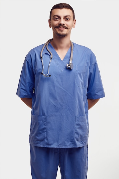 Portrait of handsome young confident arabic doctor with fancy mustache in blue isolated on white 