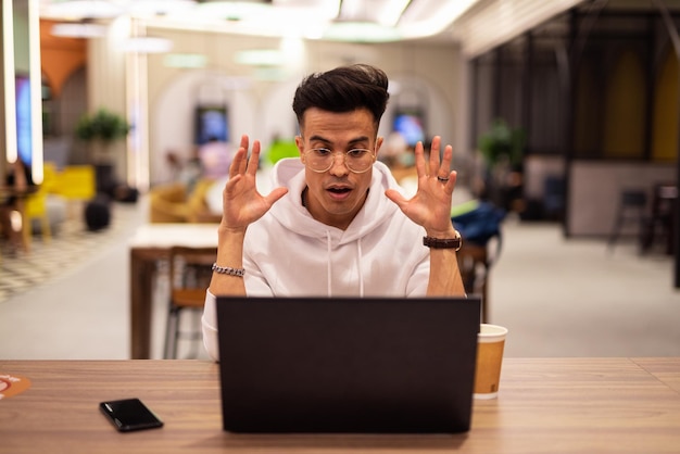 Portrait of handsome young cool man using laptop at coffee shop