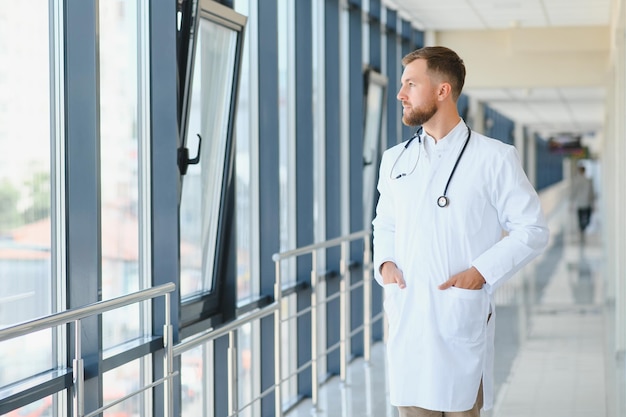 Portrait of handsome young doctor on hospital corridor