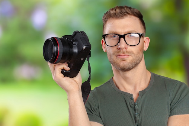 Portrait of a handsome young in glasses man with camera