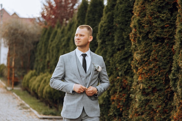 Portrait of a handsome young groom on an autumn day outdoors in an elegant suit Outdoor photo Handsome man in a business suit