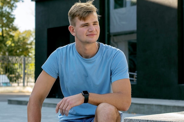 Portrait of a handsome young guy in a blue T-shirt on the street.