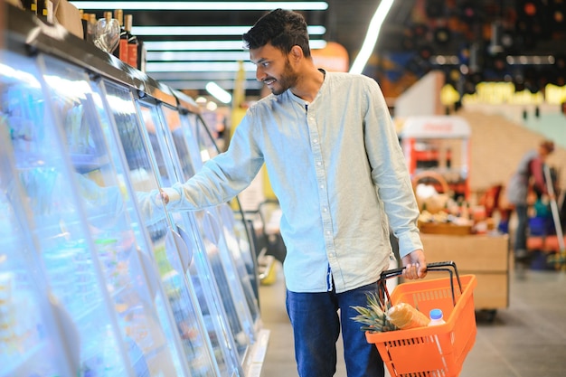 Portrait of handsome young Indian man standing at grocery shop or supermarket Closeup Selective Focus