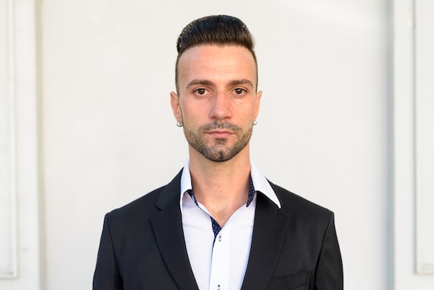 Portrait of handsome young Italian businessman outdoors in city wearing suit