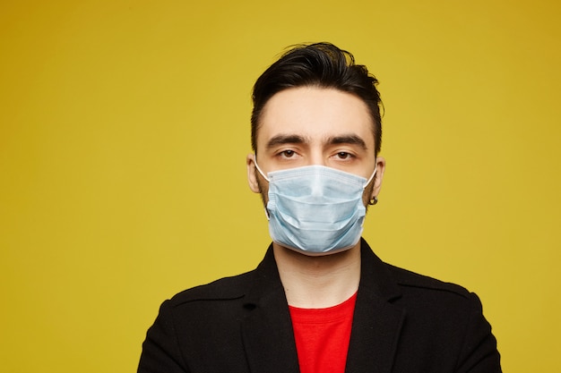 Photo portrait of handsome young man in black protective mask looking in camera. seasonal illness and seasonal flu prevention.