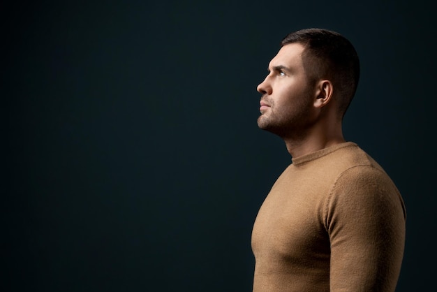 Photo portrait of handsome young man in dramatic light over dark background fashion photo