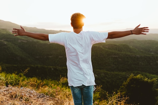 Portrait of handsome young man enjoying nature at mountain peak.