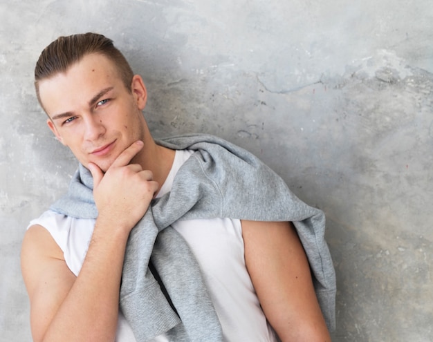 Portrait of a handsome young man, fashion model. Posing over grey wall.