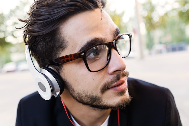 Portrait of handsome young man listening to music in the street.