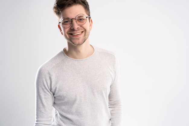 Portrait of handsome young man looking directly with smile while standing against white