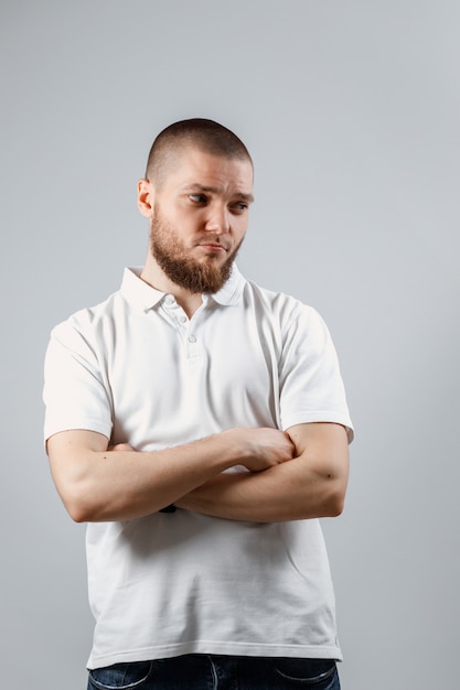 Portrait of a handsome young man looking upset to the side on gray