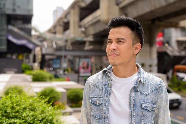 Portrait of handsome young man outdoors in city thinking