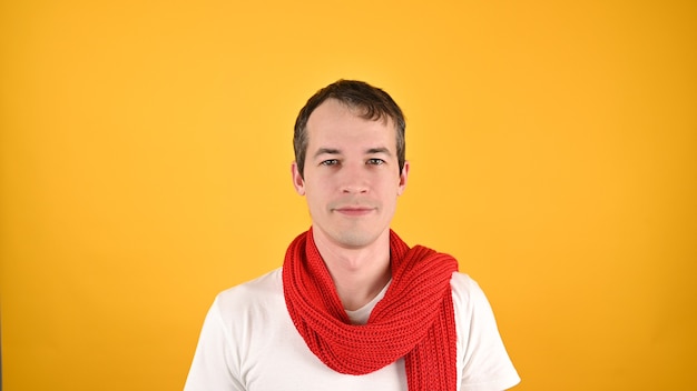 Portrait of handsome young man in red scarf and white T-shirt. Studio shot on a yellow background.