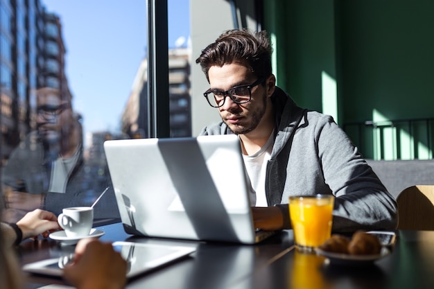 Photo portrait of handsome young man using his laptop in the coffee.