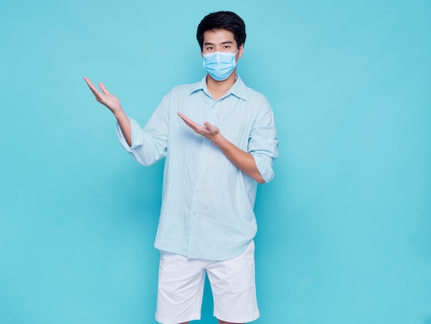 Portrait of handsome young man wearing medical mask in casual clothes pointing finger up. concept covid 19