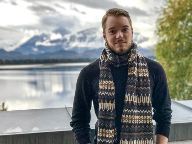 Foto ritratto di un bel giovane che indossa un silenziatore contro il lago