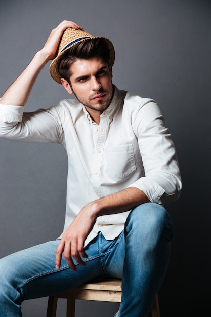 Photo portrait of handsome young man in white shirt, jeans and hat