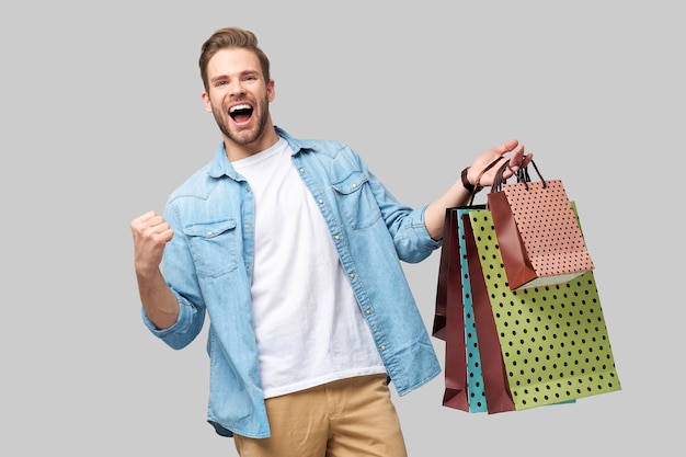 Photo portrait of a handsome young man with shopping bags.