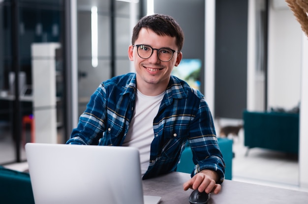 Portrait of handsome young man working remotely at home and smiling happily