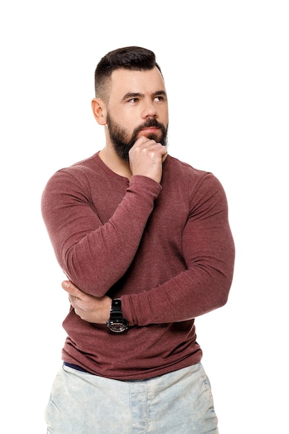 Portrait of handsome young pensive brunette man on white background. guy thinks