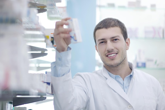 portrait of handsome young  pharmacist chemist man standing in pharmacy drugstore