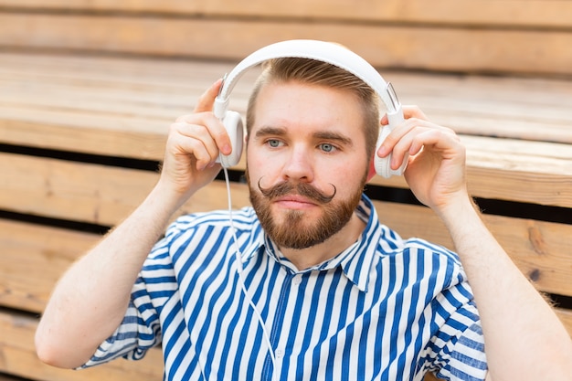 Portrait of a handsome young student guy with a mustache and a beard relaxing in a park with