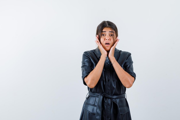 Portrait of happily surprised mexican woman in leather coat put hands on face and opened mouth isolated on white background