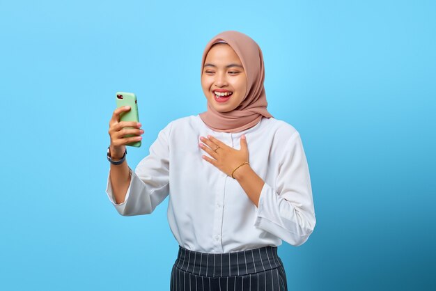 Portrait of happiness young Asian woman using mobile phone with another hand on chest