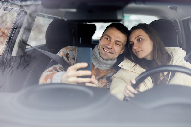 Ritratto di coppia adulta felice che si fa selfie in macchina insieme e si gode le vacanze invernali