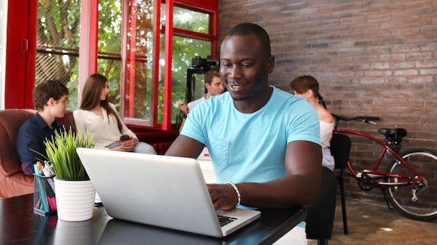 Photo portrait of a happy african american entrepreneur displaying computer in office.