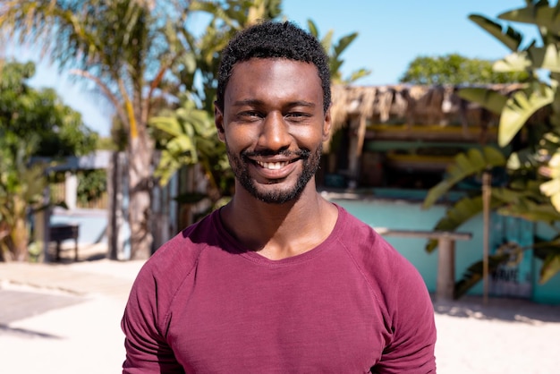 Portrait of happy african american man looking at camera and smiling at beach. Spending quality time, lifestyle, summertime and vacation concept.