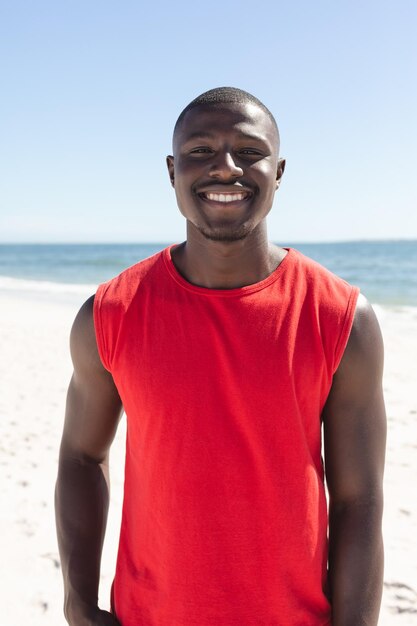 Portrait of happy african american man looking at camera and smiling on sunny beach. Summer, lifestyle, free time and vacation, unaltered.