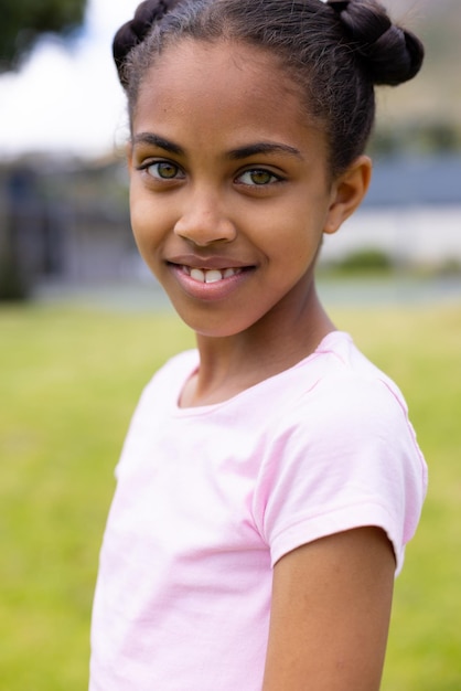 Photo portrait of happy african american schoolgirl looking at camera and smiling at school