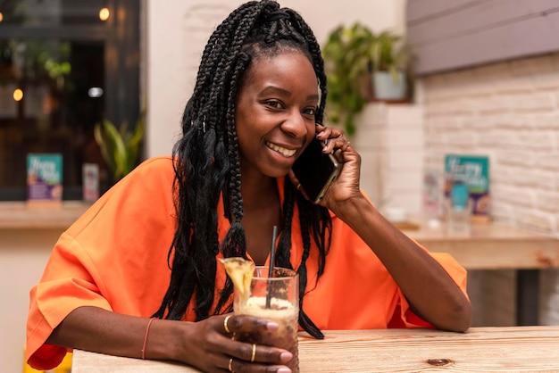 음료수를 들고 전화로 말하는 행복한 아프리카계 미국인 여성의 초상화
