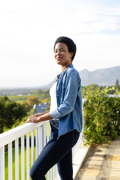 Portrait of happy african american woman staying on sunny terrace. Lifestyle, nature and domestic life, unaltered.