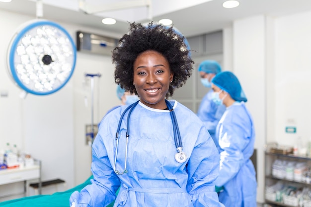 Portrait of happy african american woman surgeon standing in\
operating room ready to work on a patient female medical worker in\
surgical uniform in operation theater