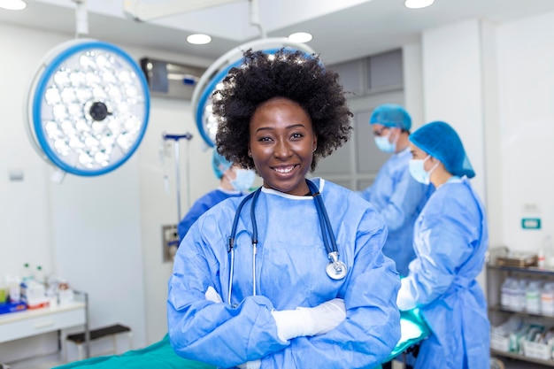 Portrait of happy african american woman surgeon standing in\
operating room ready to work on a patient female medical worker in\
surgical uniform in operation theater