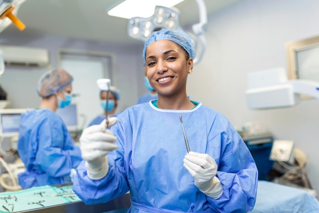 Ritratto di felice chirurgo donna afroamericana in piedi in sala operatoria pronta a lavorare su un paziente operatrice medica in uniforme chirurgica in sala operatoria