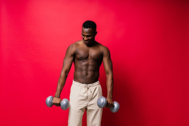 Portrait of a happy african man with dumbbells over red background